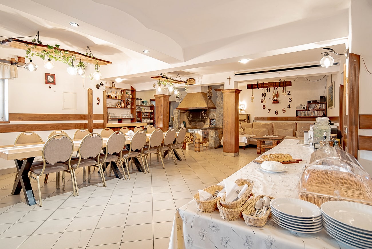 Agroturystyka Za Piecem – Duży pokój idealny na agroturystykę dla rodziny, wyposażony w stół zastawiony talerzami i miskami - idealny na wspólny wypoczynek na wsi.