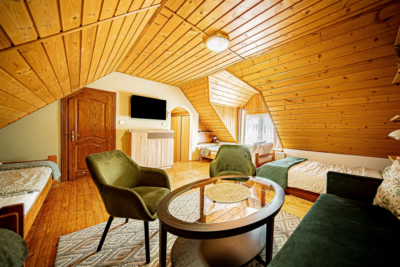 Agroturystyka Za Piecem – Przytulny pokój z dwoma łóżkami i stołem, idealny na wypoczynek na wsi oraz noclegi dla rodzin z dziećmi.