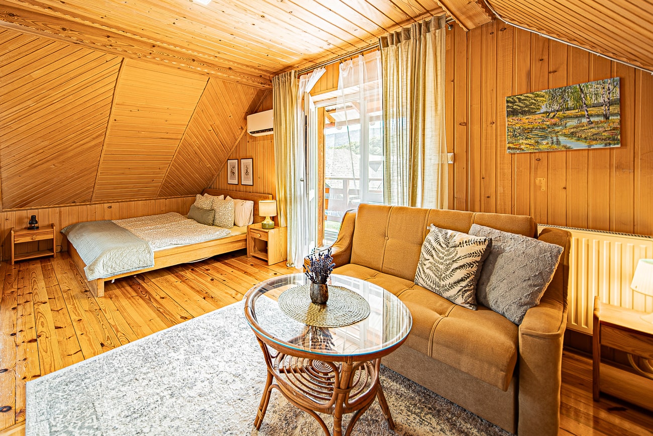 Agroturystyka Za Piecem – Przytulny pokój z dwoma łóżkami i kanapą, idealny dla agroturystyki dla rodzin lub gości szukających relaksu w spa na wsi.